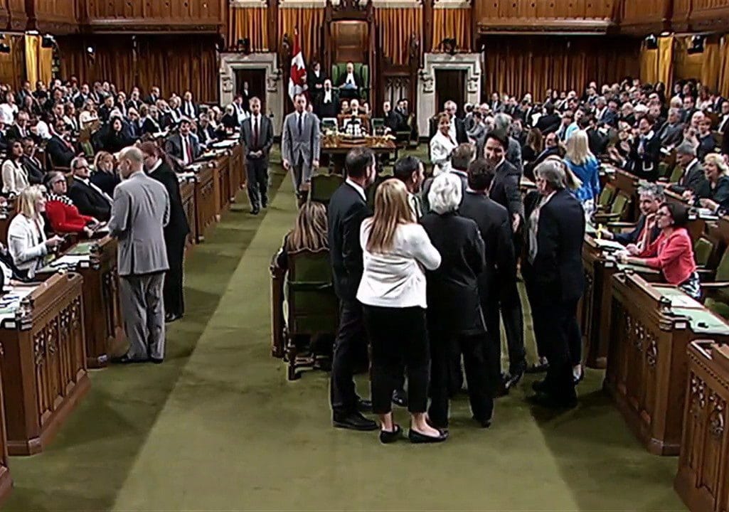 Canadian Prime Minister Justin Trudeau, face towards the camera left of centre of the frame, is shown near Opposition whip Gordon Brown in the House of Commons in Ottawa on Wednesday May 18, 2016. Footage from the Commons television feed shows Trudeau wading into a clutch of MPs, mostly New Democrats, and pulling Opposition whip Gordon Brown through the crowd in order to get a vote started. THE CANADIAN PRESS/HO-House of Commons **MANDATORY CREDIT**