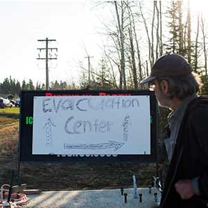 A resident of Fort McMurray walks past a evacuation centre sign put up in Anzac, Alberta, after residents were ordered to be evacuated due to a raging wildfire, May 4, 2016. (Topher Seguin/Reuters)
