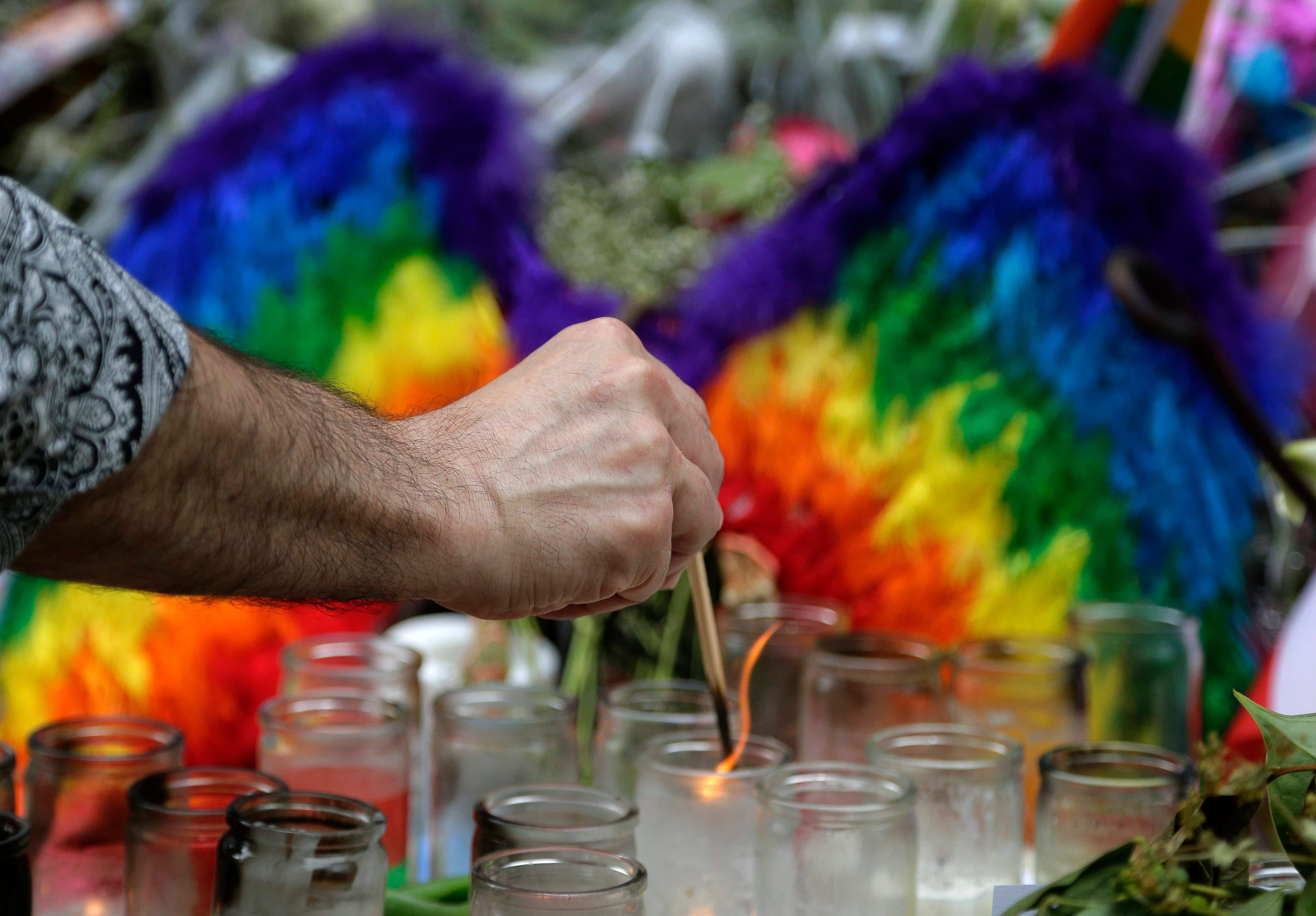 A man lights candles on a memorial outside the Stonewall Inn for victims of the Orlando Shooting, Thursday, June 16, 2016, in New York. Members of the United Nations' LGBT Core Group met at the bar on Thursday. (AP Photo/Julie Jacobson)