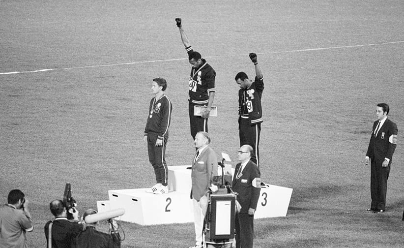 Tommie Smith and John Carlos, gold and bronze medalists in the 200-meter run at the 1968 Olympic Games, engage in a victory stand protest against unfair treatment of blacks in the United States. With heads lowered and black-gloved fists raised in the black power salute, they refuse to recognize the American flag and national anthem. Australian Peter Norman is the silver medalist. (Bettmann/Getty Images)
