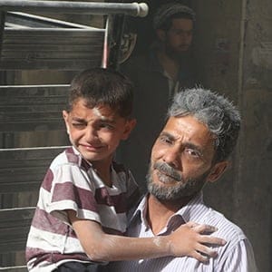 A man carries a boy after the Syrian regime forces airstrikes targeted over Aleppo's opposition controlled Kellese district, Syria on July 09, 2016. At least 5 people wounded in the airstrike. (Ibrahim Ebu Leys/Anadolu Agency/Getty Images)