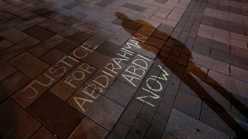 A man casts a shadow near a message written in chalk during a vigil for Abdirahman Abdi, a Somali immigrant to Canada who died after being hospitalized in critical condition following his arrest by Canadian police, in Ottawa, Ontario, Canada, July 26, 2016. (Chris Wattie/Reuters)