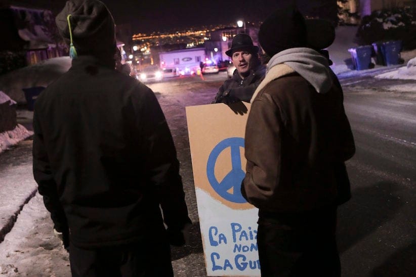 Martin St. Louis holds a sign that reads "la paix pas la guerre" (peace, not war) near a Quebec city mosque after a shooting on Sunday January 29, 2017. THE CANADIAN PRESS/Francis Vachon