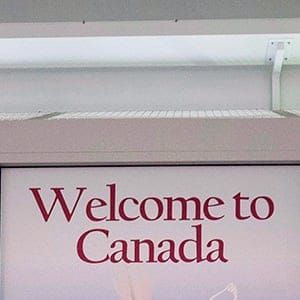 A Canadian Border Services agent walks past a welcoming sign at Gate 521 at Pearson International Airport in Toronto. (Darren Calabrese/CP)
