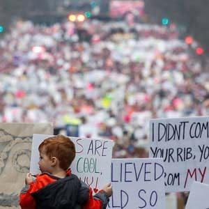 A boy, sitting on the shoulders of a man,  is seen amid placards as he and others head towards a sea of activists taking part in the Women's March in opposition to the agenda and rhetoric of President Donald Trump in Washington, D.C., U.S. on January 21, 2017. (Adrees Latif/Reuters)