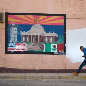 A man walks past a burial of US/Mexico cooperation, in which the American flag has been crossed-out, in Nogales, Arizona, on February 17, 2017, on the US/Mexico border. (Jim Watson/AFP/Getty Images)