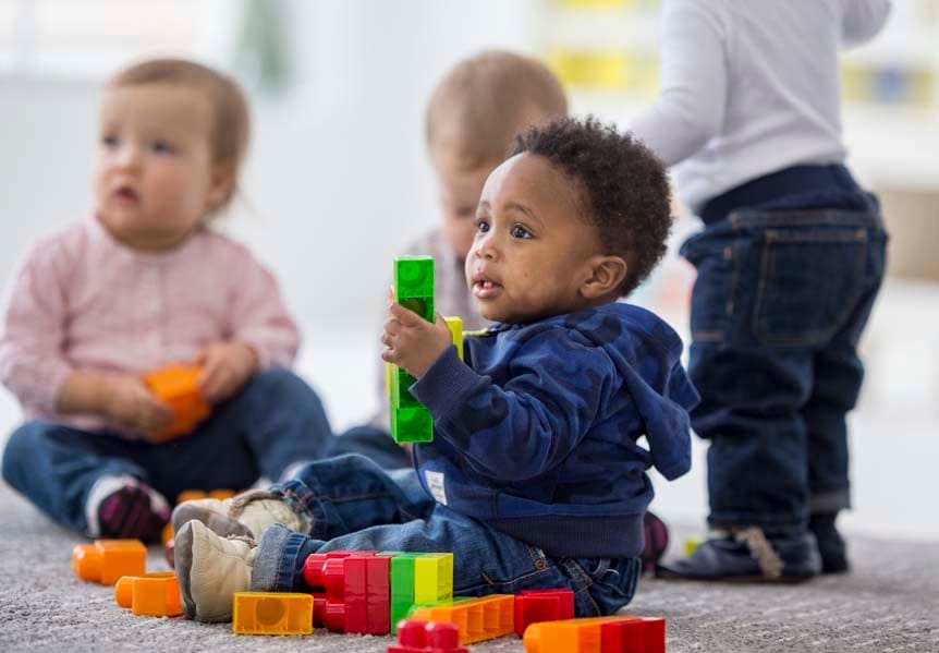 Babies playing with toys indoors at a daycare. (FatCamera)
