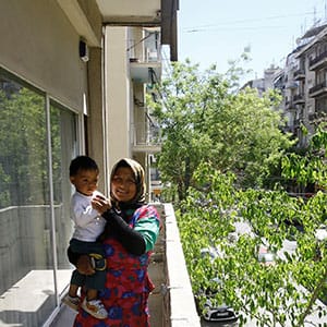 A refugee woman stands with her baby at the balcony of City Plaza hotel reopened for refugees by an organization which support refugees in Athens Greece on April 26, 2016.

 (Ayhan Mehmet/Anadolu Agency/Getty Images)