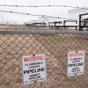 Pipes and tanks are seen behind a barbed wire fence at the Kinder Morgan Trans Mountain facility in Edmonton, Alta., Thursday, April 6, 2017. (Jonathan Hayward/CP)