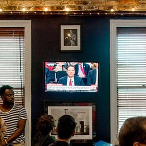 TOPSHOT - Spectators and patrons at Shaw's Tavern in northwest Washington, DC, watch as former Federal Bureau of Investigation (FBI) Director James Comey testifies before the Senate Intelligence Committee on June 8, 2017. / AFP PHOTO / JIM WATSON        (Photo credit should read JIM WATSON/AFP/Getty Images)