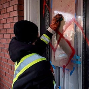 A graffiti removal worker cleans anti-Semitic graffiti, including a swastika, that was spray painted on the door of The Glebe Minyan and home of Rabbi Anna Maranta, on Tuesday, Nov. 15, 2016 in Ottawa. (Justin Tang/CP)