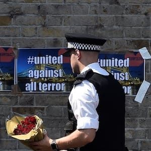 A police officer carries flowers to leave alongside of messages near to where a van was driven at muslims in Finsbury Park, North London, Britain, June 19, 2017. REUTERS/Hannah McKay - RTS17POH