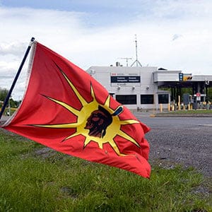 A Mohawk Warrior flag flies in front of the Canadian border crossing station as they block the Seaway Bridge in the Mohawk community of Akwesasne on Cornwall Island, Ont., Monday, June 1, 2009. The Mohawks are protesting the arming of Canada Customs guards with guns. (Ryan Remiorz/CP)