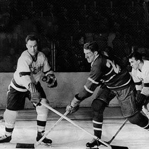 Canadian hockey player Red Kelly (left) of the Detroit Red Wings battles with Paul Masnick of the Montreal Canadiens for an airborne puck while Red Wing Marty Pavelich (right) skates in to join the action during the final game of the Stanley Cup in Detroit, Michigan, April 16, 1954. Detroit went on to win the game and the Cup. (Bruce Bennett Studios/Getty Images)
