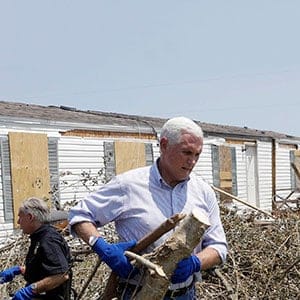 Vice President Mike Pence, center right, and Texas Gov. Greg Abbott, center in wheel chair, help move debris during a visit to an area hit by Hurricane Harvey, Thursday, Aug. 31, 2017, in Rockport, Texas. (Eric Gay/AP)