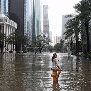 Mia Herman has an acquaintance take a photo of her sitting on a fire hydrant on a flooded street as Hurricane Irma hits the area on Sunday September 10, 2017 in Miami, FL. (Matt McClain/The Washington Post/Getty Images)