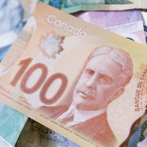 The days of paper money are fast ending.  The new Canadian polymer 100 dollar bill atop a pile of the old paper bills.