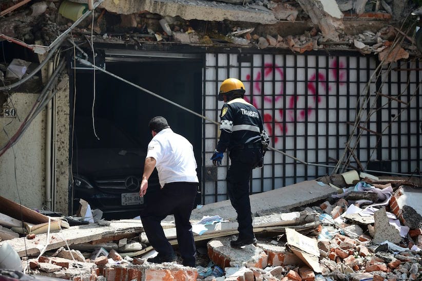A traffic controller and a security guard look for possible victims at a building which collapsed during a quake in Mexico City on September 19, 2017.
A powerful earthquake shook Mexico City on Tuesday, causing panic among the megalopolis' 20 million inhabitants on the 32nd anniversary of a devastating 1985 quake. The US Geological Survey put the quake's magnitude at 7.1 while Mexico's Seismological Institute said it measured 6.8 on its scale. The institute said the quake's epicenter was seven kilometers west of Chiautla de Tapia, in the neighboring state of Puebla.
 / AFP PHOTO / Ronaldo SCHEMIDT        (Photo credit should read RONALDO SCHEMIDT/AFP/Getty Images)