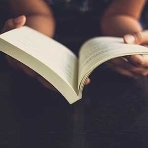 Woman place her arms on her lap and open book to read