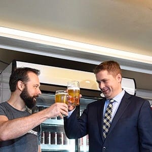 Conservative Party Leader Andrew Scheer and Michael Sirko, left, co-founder of the Vimy Brewing Company, clink beer glasses during a photo opportunity before a press conference launching the Save Local Business campaign in response to the government's tax changes for small businesses, at Vimy Brewing Company in Ottawa on Tuesday, Sept. 19, 2017. (Justin Tang/CP)