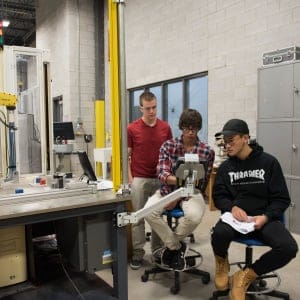 Nathan Wells, left, Jake Mihkelson, and Zhenlin Wangat work on a robot at Conestoga College in an Introduction to Robotics lab in Cambridge, Ontario. (Photograph by Hannah Yoon)