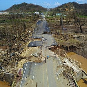 A man rides his bicycle through a damaged road in Toa Alta, west of San Juan, Puerto Rico, on September 24, 2017 following the passage of Hurricane Maria. (Ricardo Arduengo/AFP/Getty Images)