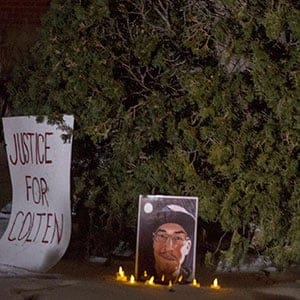 Michelle Stewart, a supporter of the Boushie family, looks at a sign and photo of Colten Boushie in front of the Court of Queen's Bench on the day of closing arguments and first day of jury in deliberation in the trial of Gerald Stanley, the farmer accused of killing the 22-year-old Indigenous man, in Battleford, Sask., Thursday, February 8, 2018. THE CANADIAN PRESS/Liam Richards