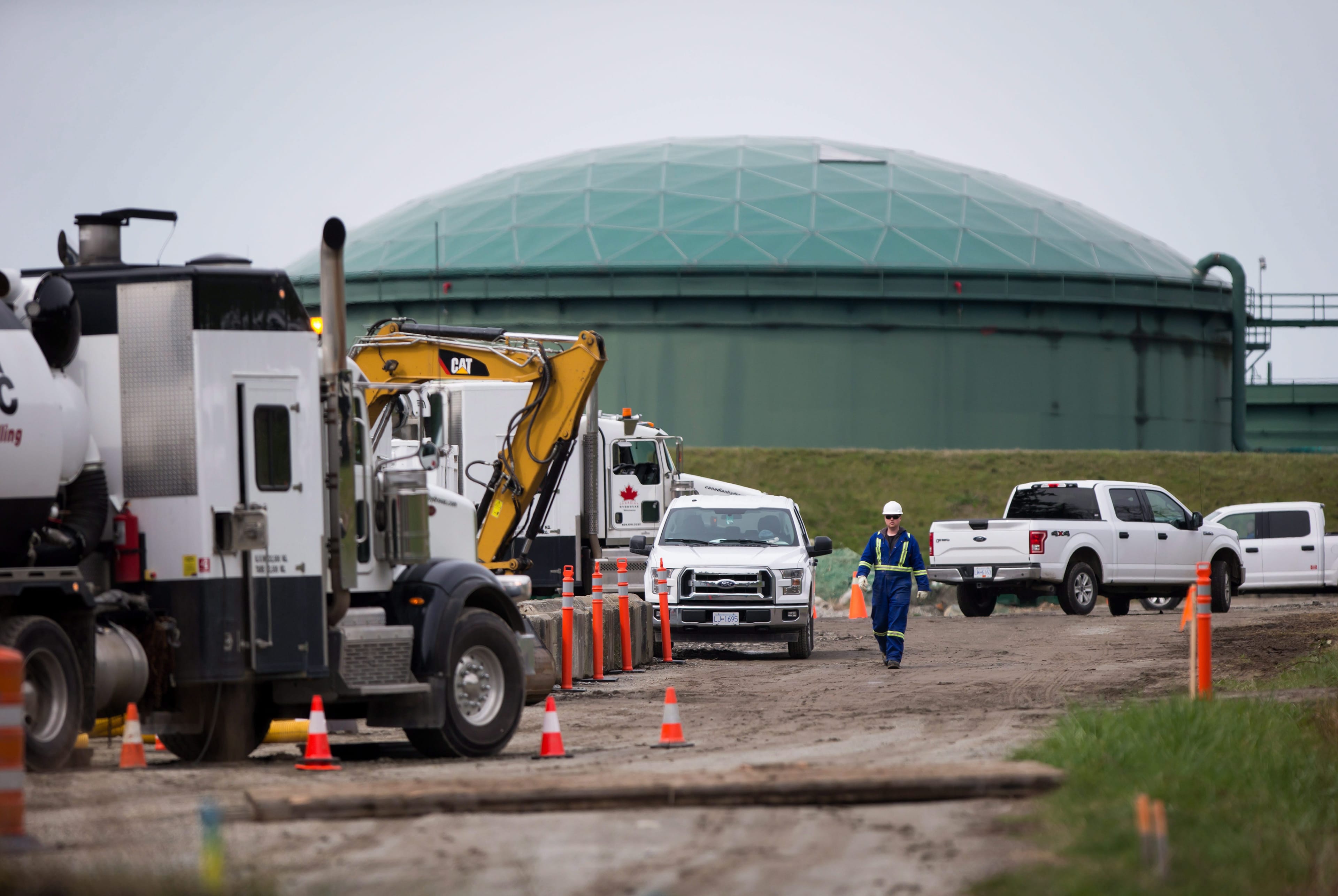 A worker walks past heavy equipment as work continues at Kinder Morgan's facility in preparation for the expansion of the Trans Mountain Pipeline, in Burnaby, B.C., on Monday April 9, 2018. The Houston, Texas, based company announced Sunday it has suspended all non-essential activities and related spending on the pipeline expansion that would carry Alberta bitumen to an export terminal near Vancouver. THE CANADIAN PRESS/Darryl Dyck
