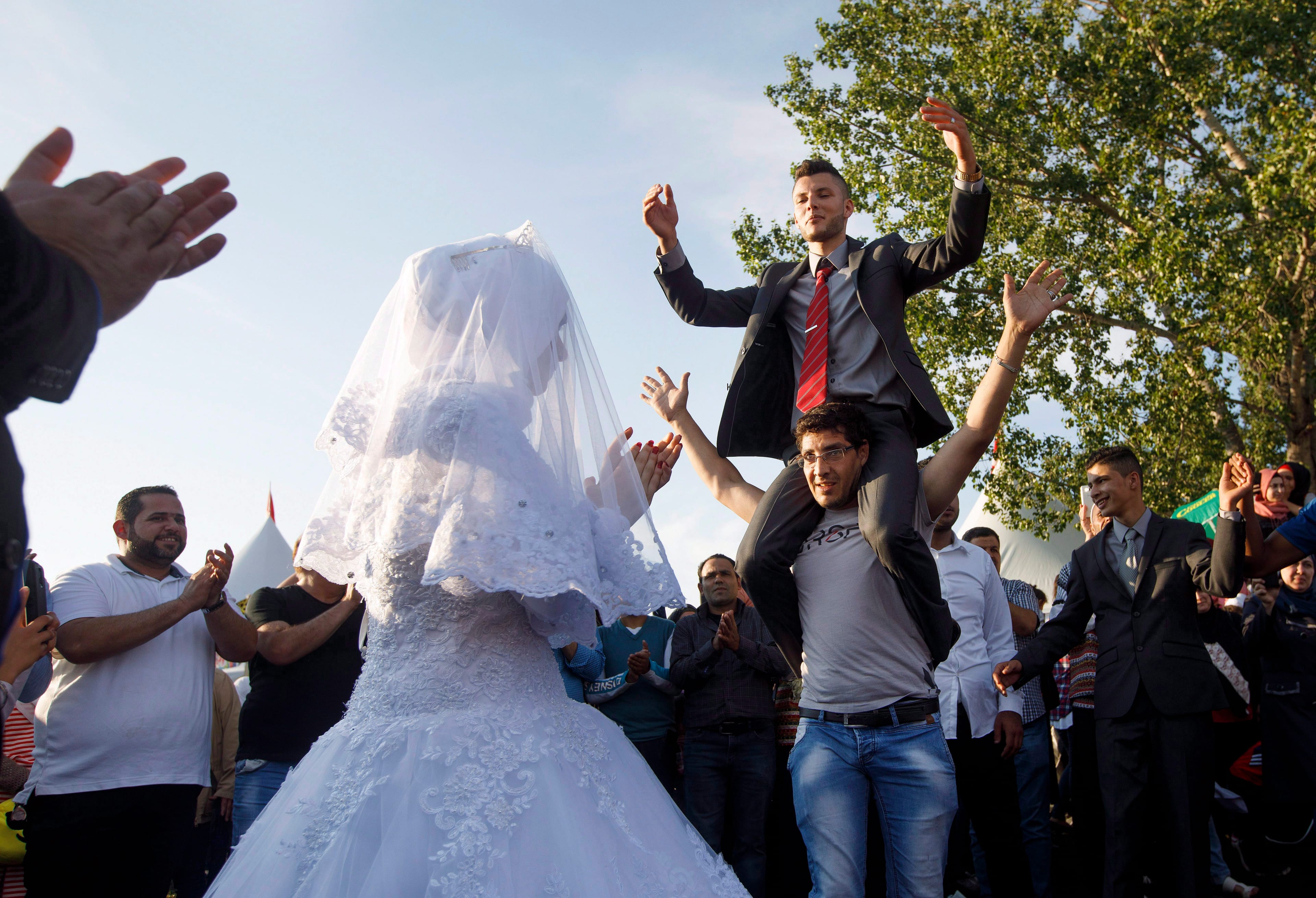 Manar Shakeouf watches as her husband Mostafa Khalis is carried around during a traditional Syrian wedding ceremony in Edmonton, Alta, on Saturday Aug. 5, 2017. (THE CANADIAN PRESS/Jason Franson)