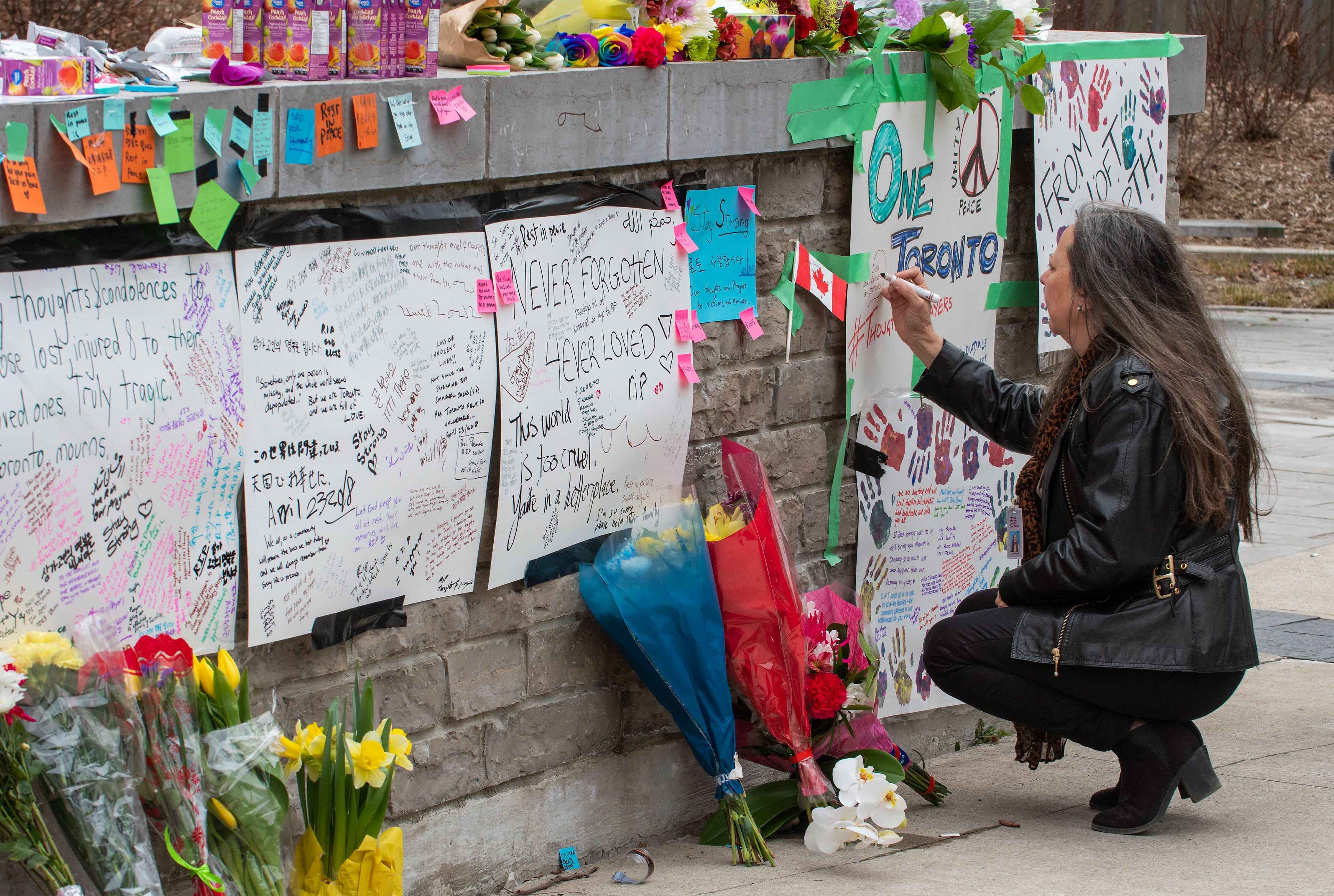 A woman writes a message at a makeshift memorial across the street from where a man in a rented van plowed into pedestrians on Yonge Street in northern Toronto, Canada, 24 April 2018. Ten people were killed and 15 injured on 23 April 2018, after a man driving a rented van mowed down pedestrians along a one-mile stretch of Yonge Street.  EPA/WARREN TODA