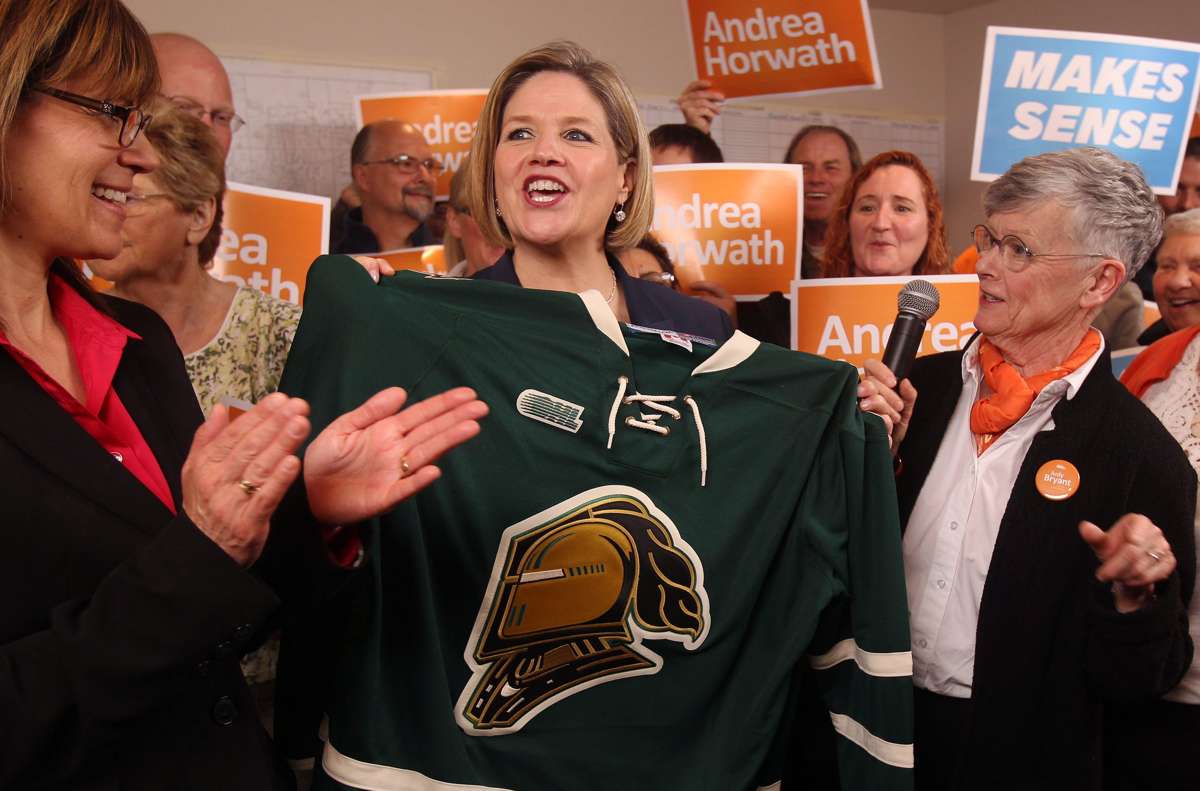 Ontario NDP Leader Andrea Horwath holds up a London Knights CHL hockey jersey as she cheers on the team at a campaign stop with London-Fanshawe MPP Teresa Armstrong, left, and London North Centre candidate Judy Bryant in London, Ont., Friday, May 16, 2014. London is hosting the Memorial Cup CHL championship tournament starting tonight. THE CANADIAN PRESS/Dave Chidley