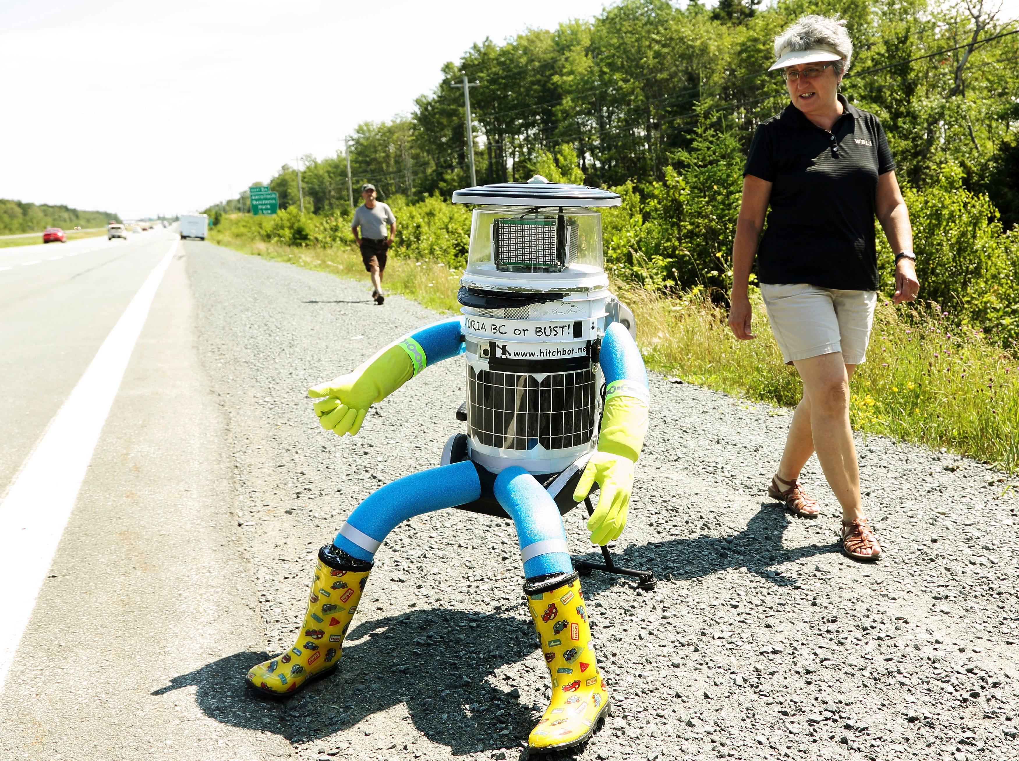 Anne Saulnier (R) and her husband Brian prepare to give a ride to the anthropomorphic robot named hitchBOT on Highway 102  outside of Halifax, Nova Scotia, July 27, 2014. The hitch hiking robot is part of a social experiment to see if strangers will help hitchBOT complete its 6,000 kilometer journey from Halifax to Victoria, British Columbia. (Paul Darrow/Reuters)
