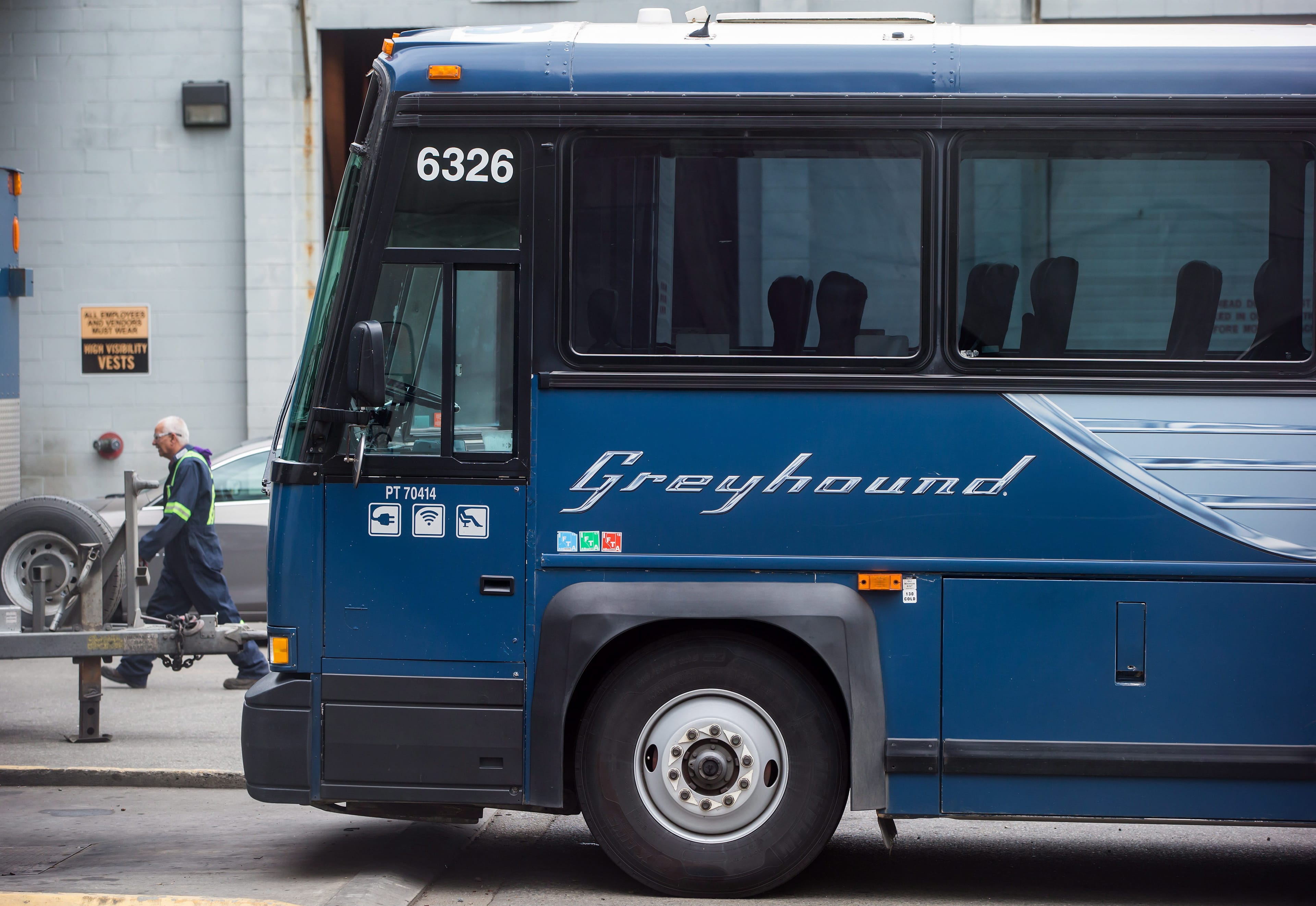 A worker walks past a Greyhound bus sitting idle, in Vancouver, on Monday July 9, 2018. Greyhound Canada says it is ending its passenger bus and freight services in Alberta, Saskatchewan and Manitoba, and cancelling all but one route in B.C. -- a U.S.-run service between Vancouver and Seattle. As a result, when the changes take effect at the end of October, Ontario and Quebec will be the only regions where the familiar running-dog logo continues to grace Canadian highways. THE CANADIAN PRESS/Darryl Dyck