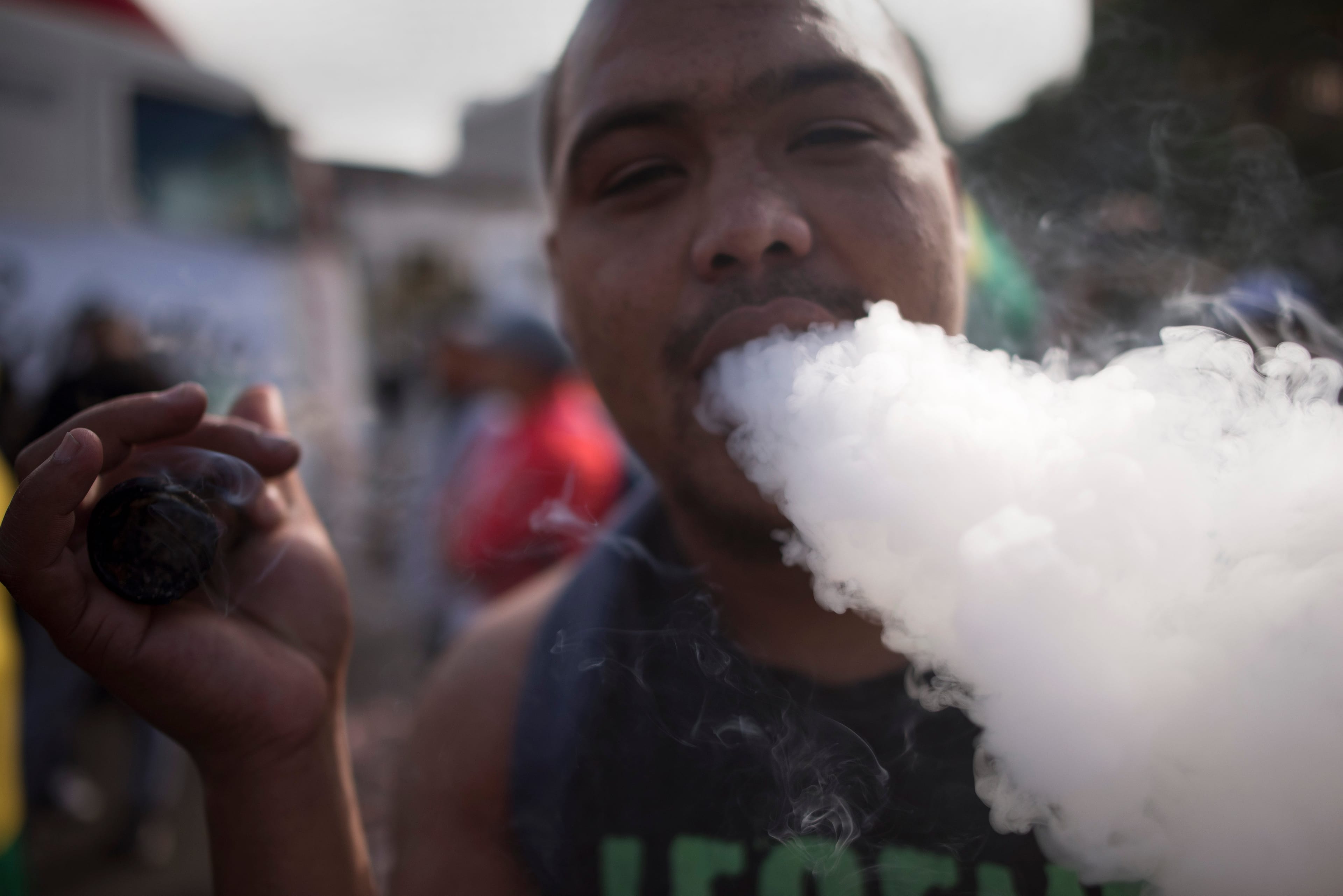 A man exhales smoke as he smokes marijuana out of a bottle-neck pipe. (Photo: RODGER BOSCH/AFP/Getty Images)