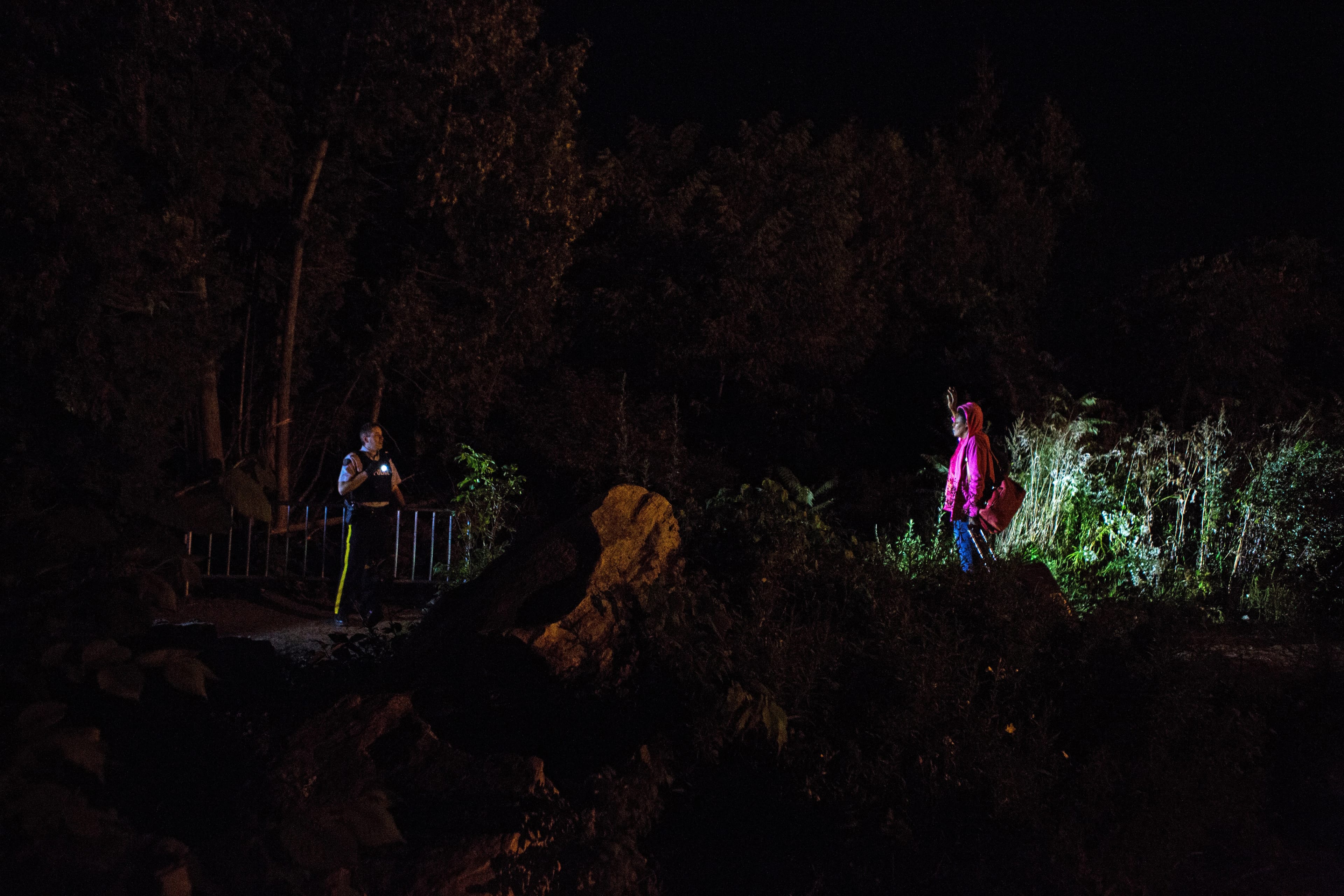 A woman originally from Haiti who has been living in the U.S. as an undocumented immigrant for several years prays under her breath as she raises her hands in front of a Canadian police officer before crossing illegally into Canada near Lacolle, Que. (Chris Donovan)