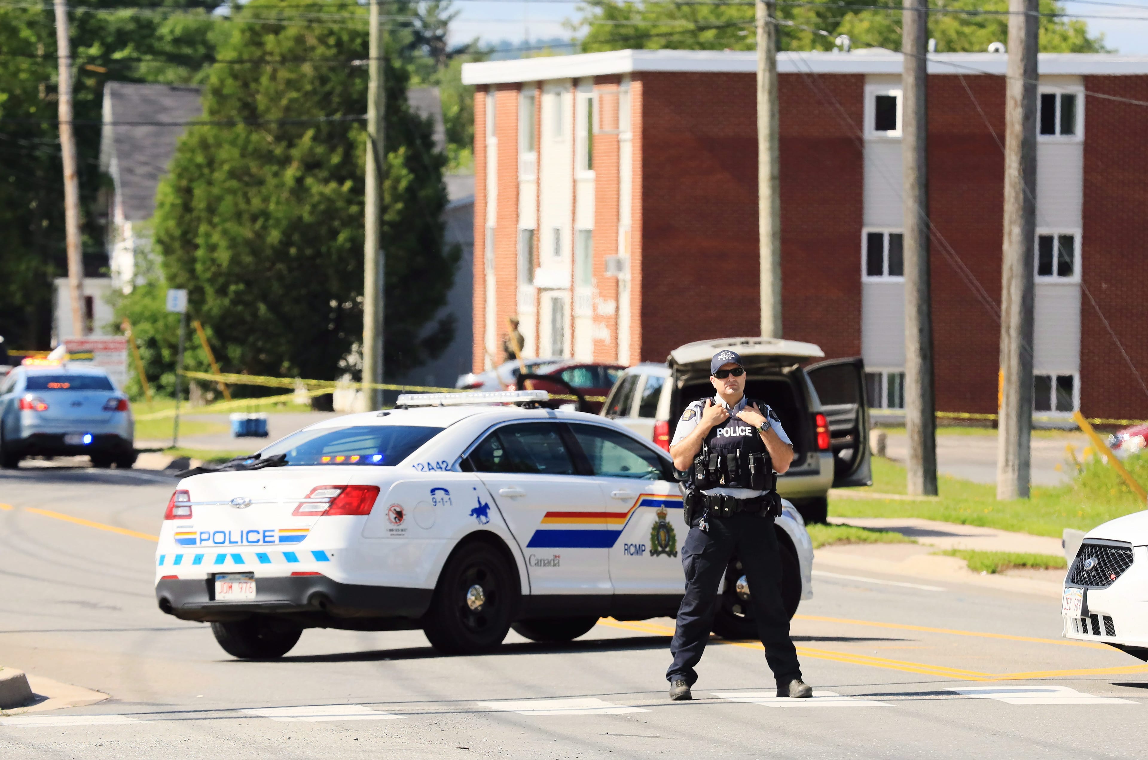 Police and RCMP officers survey the area of a shooting in Fredericton, N.B. on Friday, August 10, 2018. THE CANADIAN PRESS/Keith Minchin