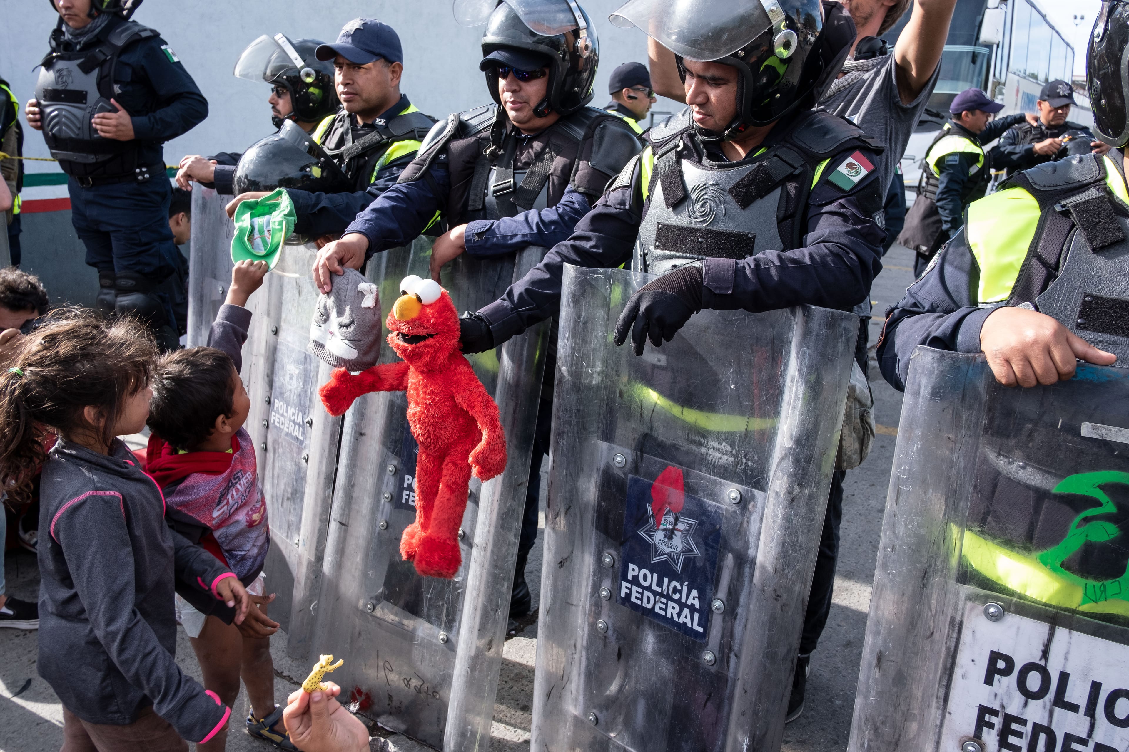 Mexican federal police officers cheer up migrant children from Central America at El Chaparral port of entry on the U.S.-Mexico border (Guillermo Arias/AFP/Getty Images)