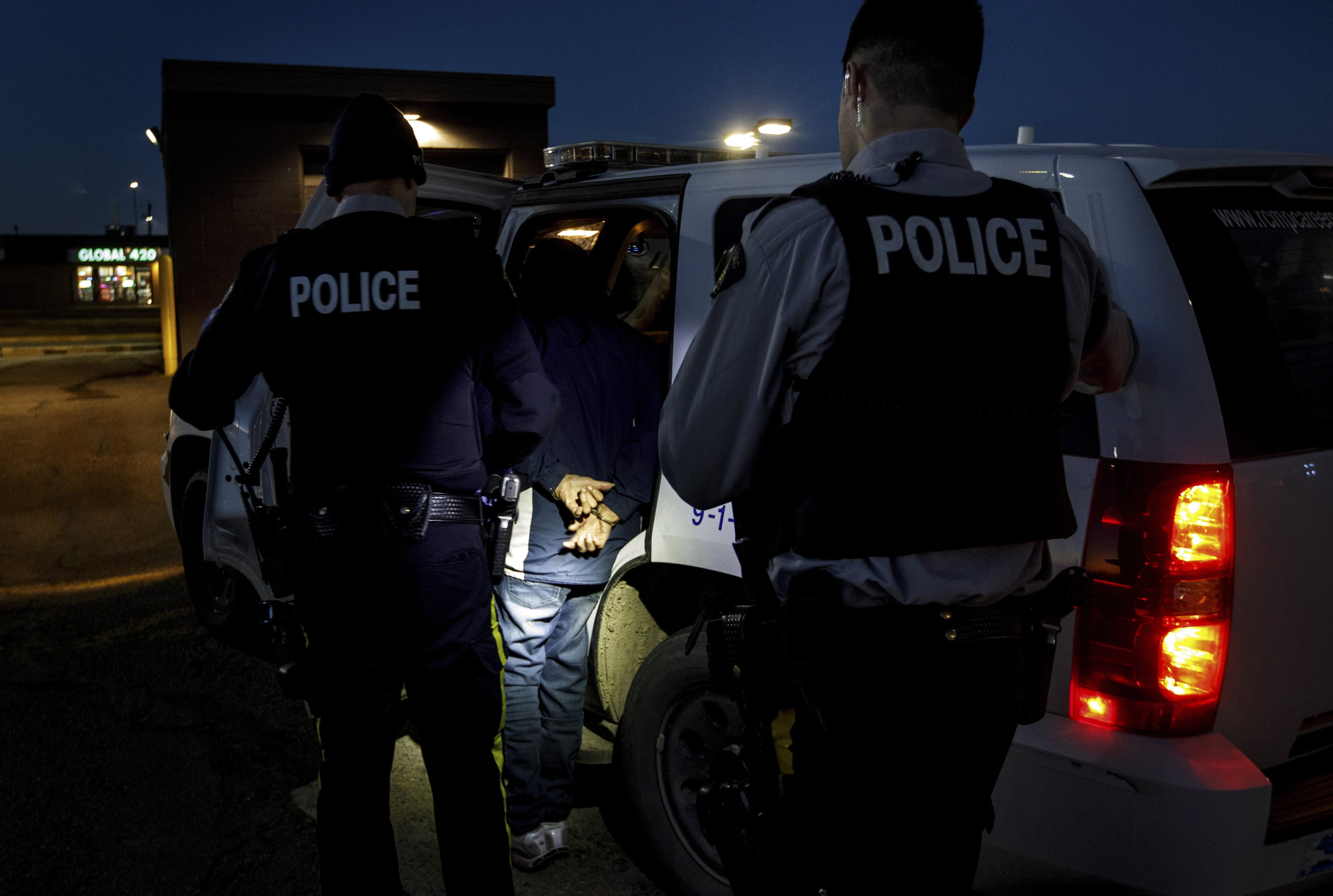 RCMP officers arrest a woman for public drunkenness in Wetaskiwin, Alta., on Oct. 23, 2018. (Photo by Jason Franson)