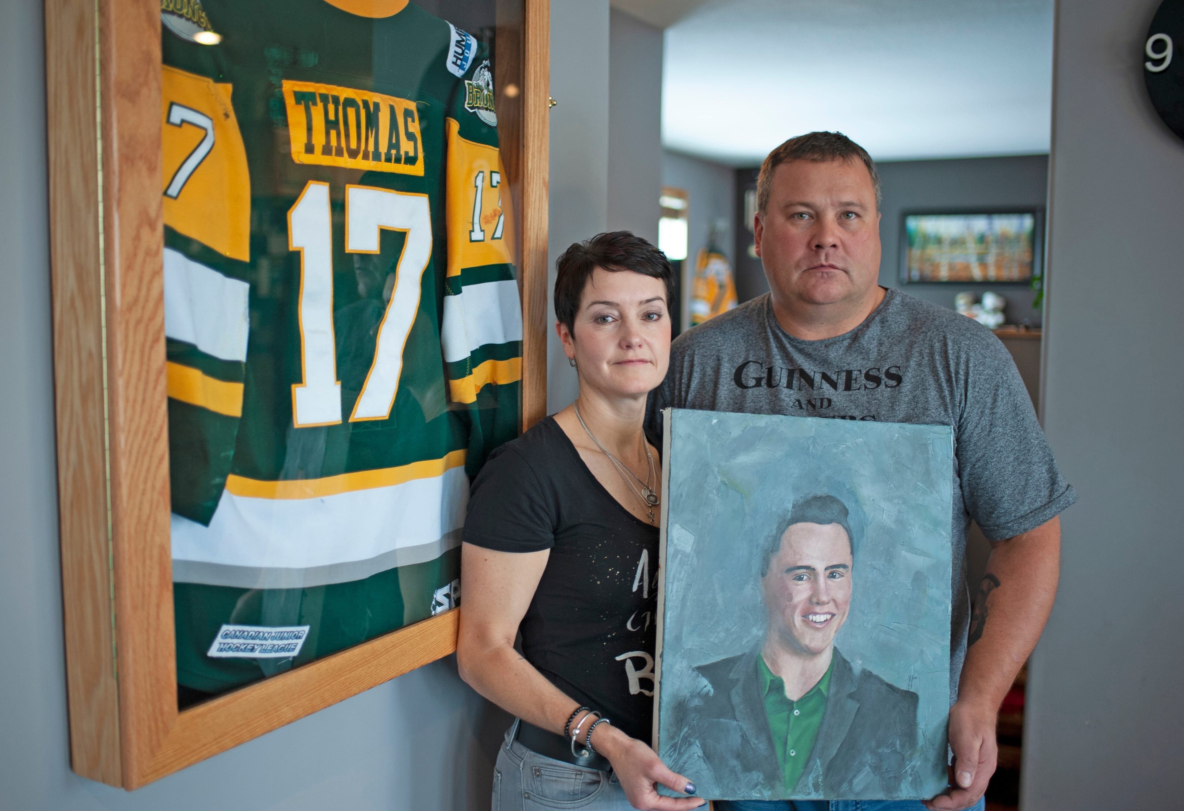Laurie and Scott Thomas pose with a painting of their late son, Evan, in their Saskatoon home. (Photograph by Mark Taylor)