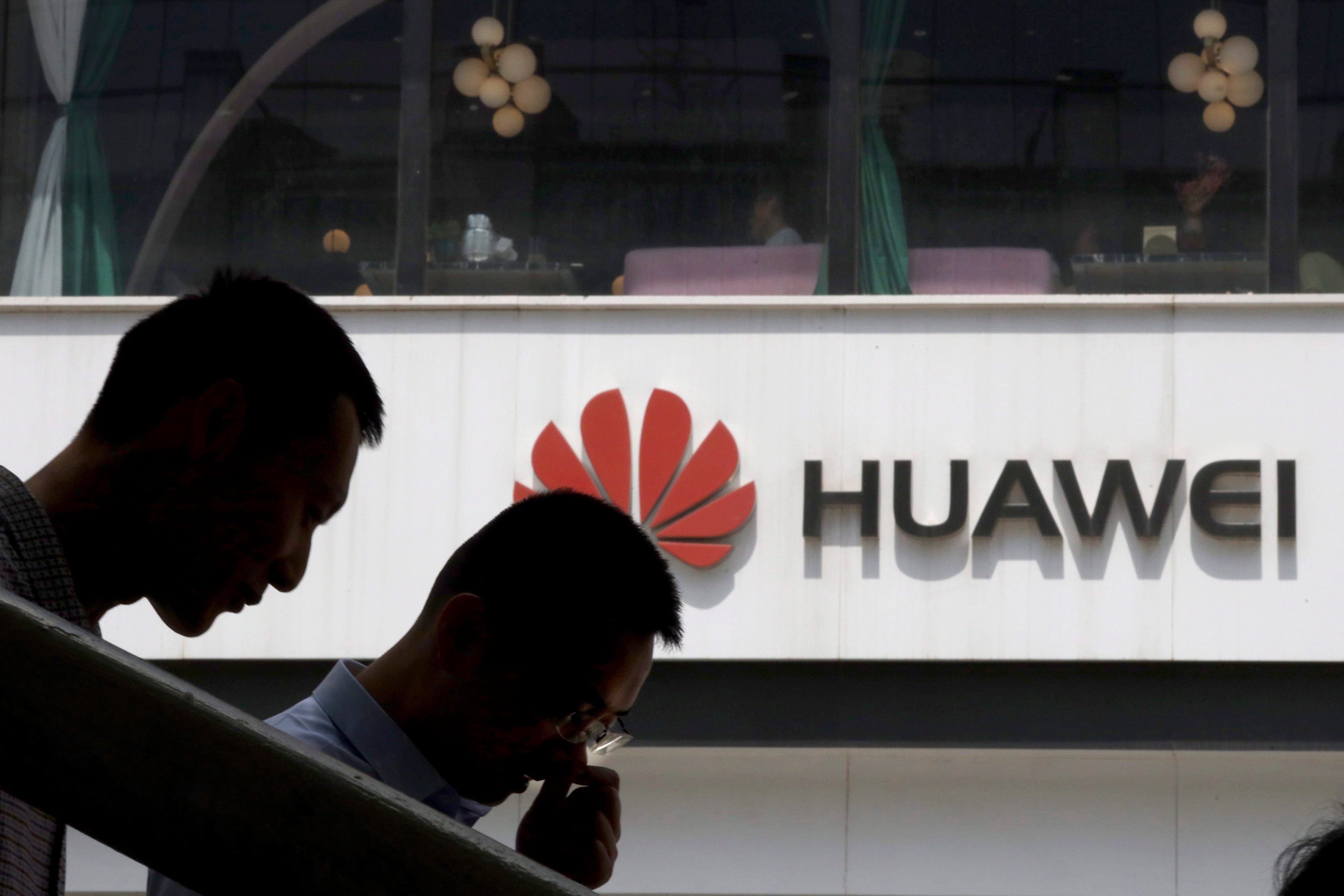 In this May 16, 2019, photo, Chinese men pass by a Huawei retail shop in Beijing. (Ng Han Guan/AP)