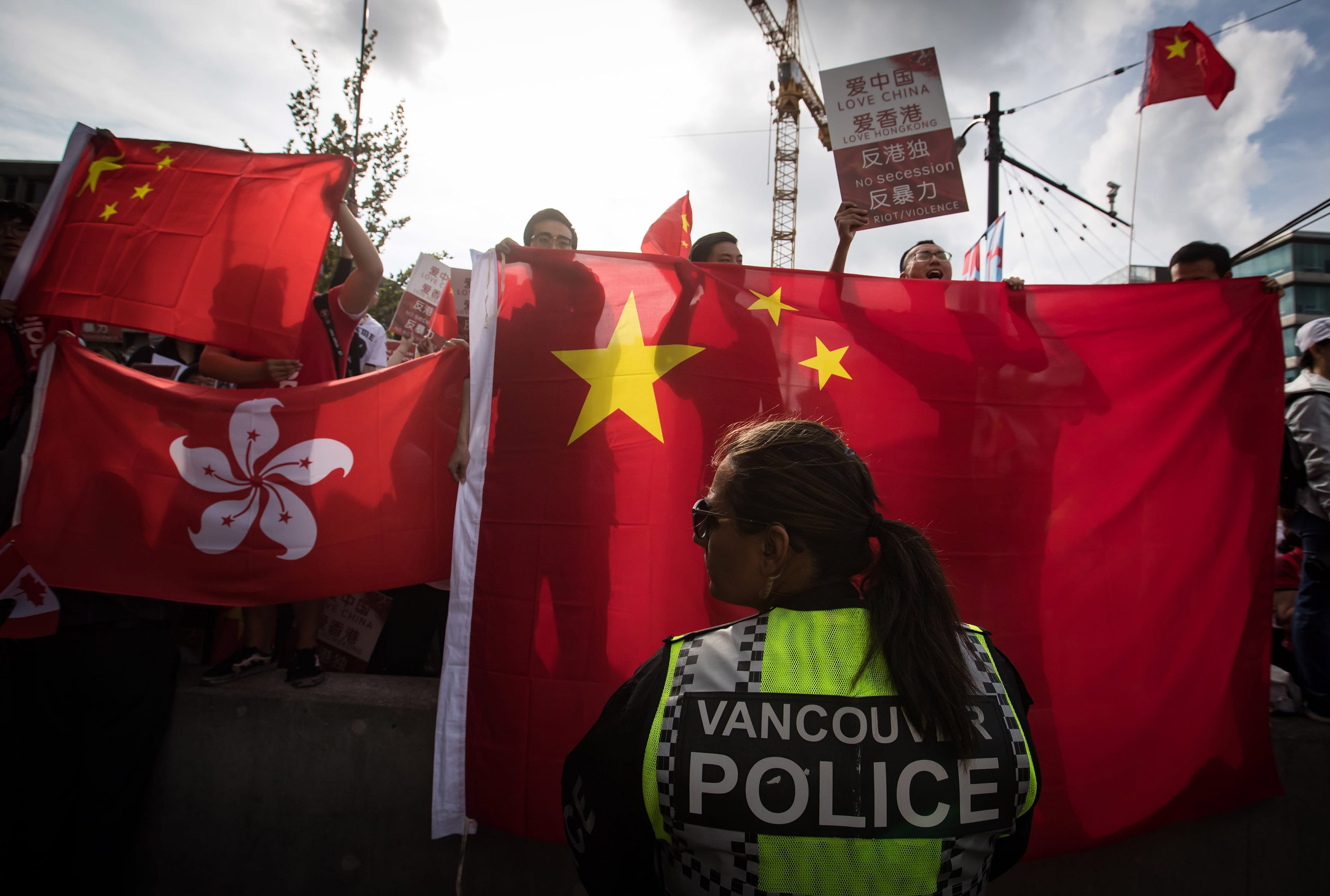 A police officer watches as pro-China counter-protesters shout at Hong Kong anti-extradition bill protesters holding a rally, in Vancouver, on Saturday August 17, 2019. (Darryl Dyck/CP)