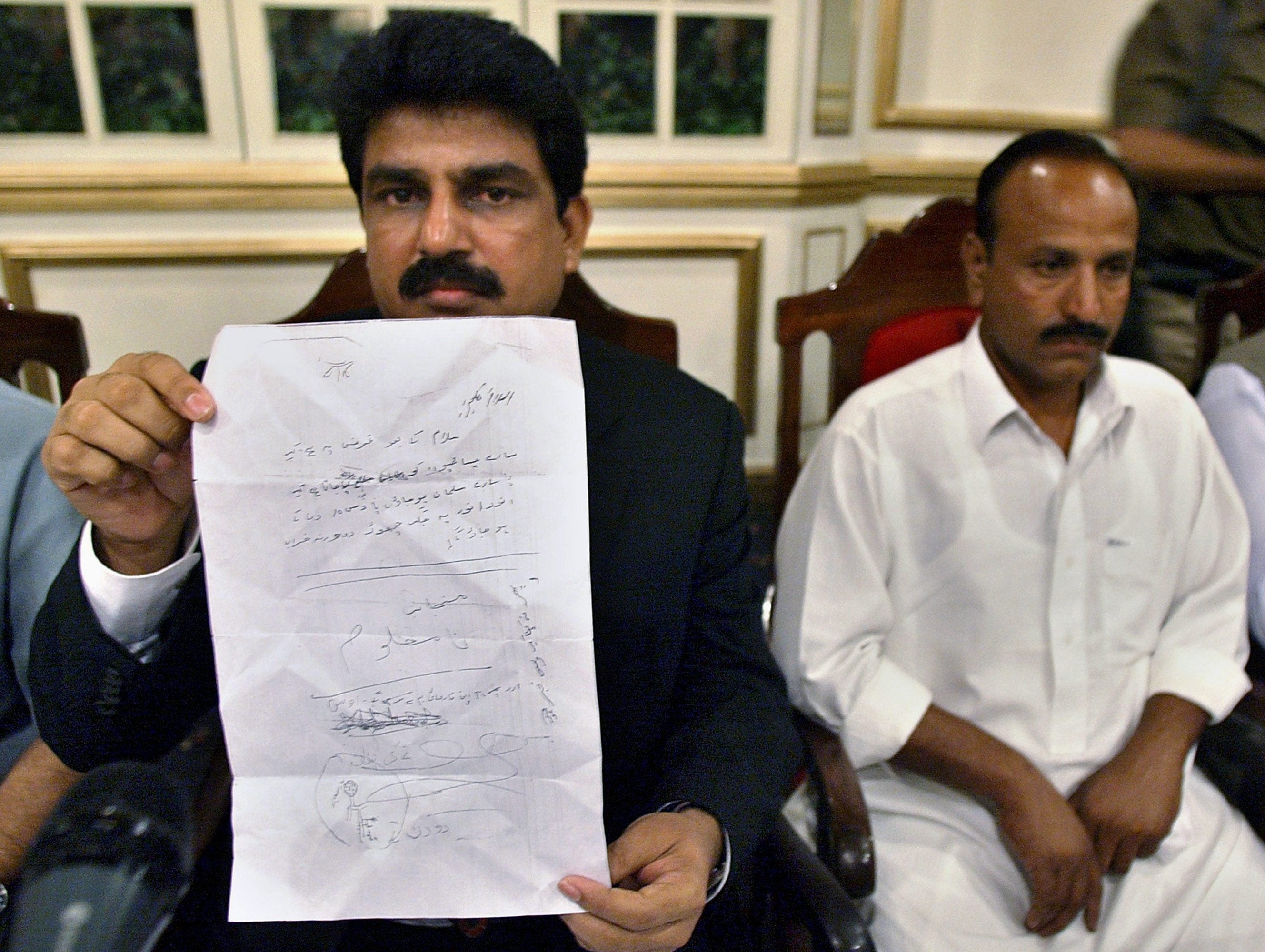 Shahbaz Bhatti, left, is seen in 2007 holding a threatening letter a Christian received in a pro-Taliban town where  Pakistani Christians were ordered to convert to Islam (Anjum Naveed/AP)