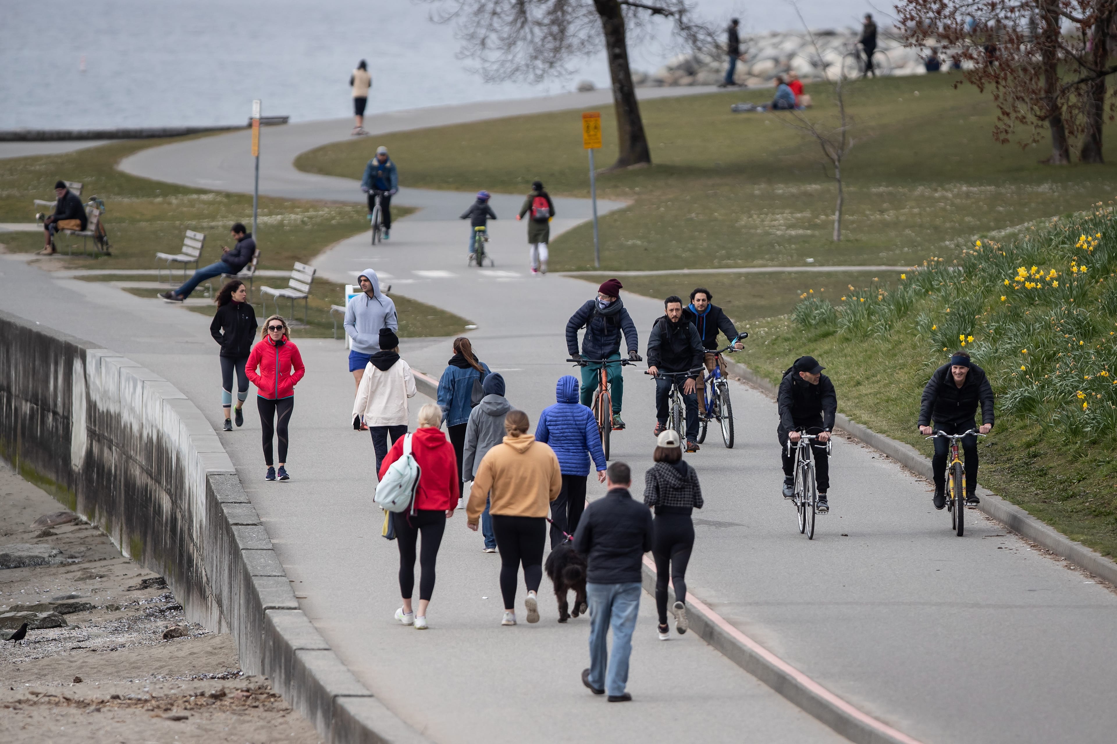 People walk and cycle on the seawall between English Bay and Sunset Beach, in Vancouver, on Sunday, March 22, 2020. (Darryl Dyck/CP)