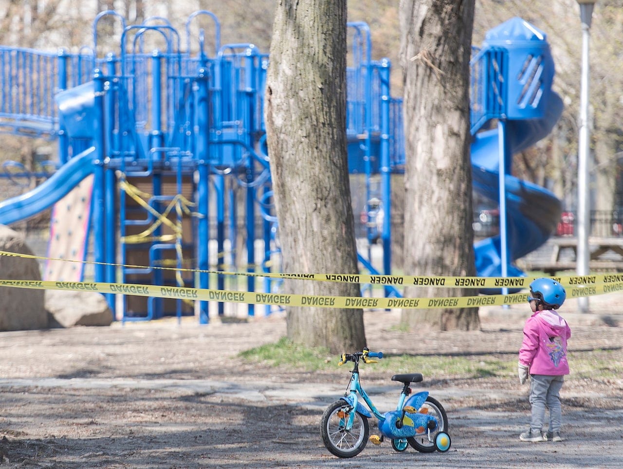 A young child stands outside the entrance to a playground in Montreal, Sunday, May 3, 2020. (Graham Hughes/CP)