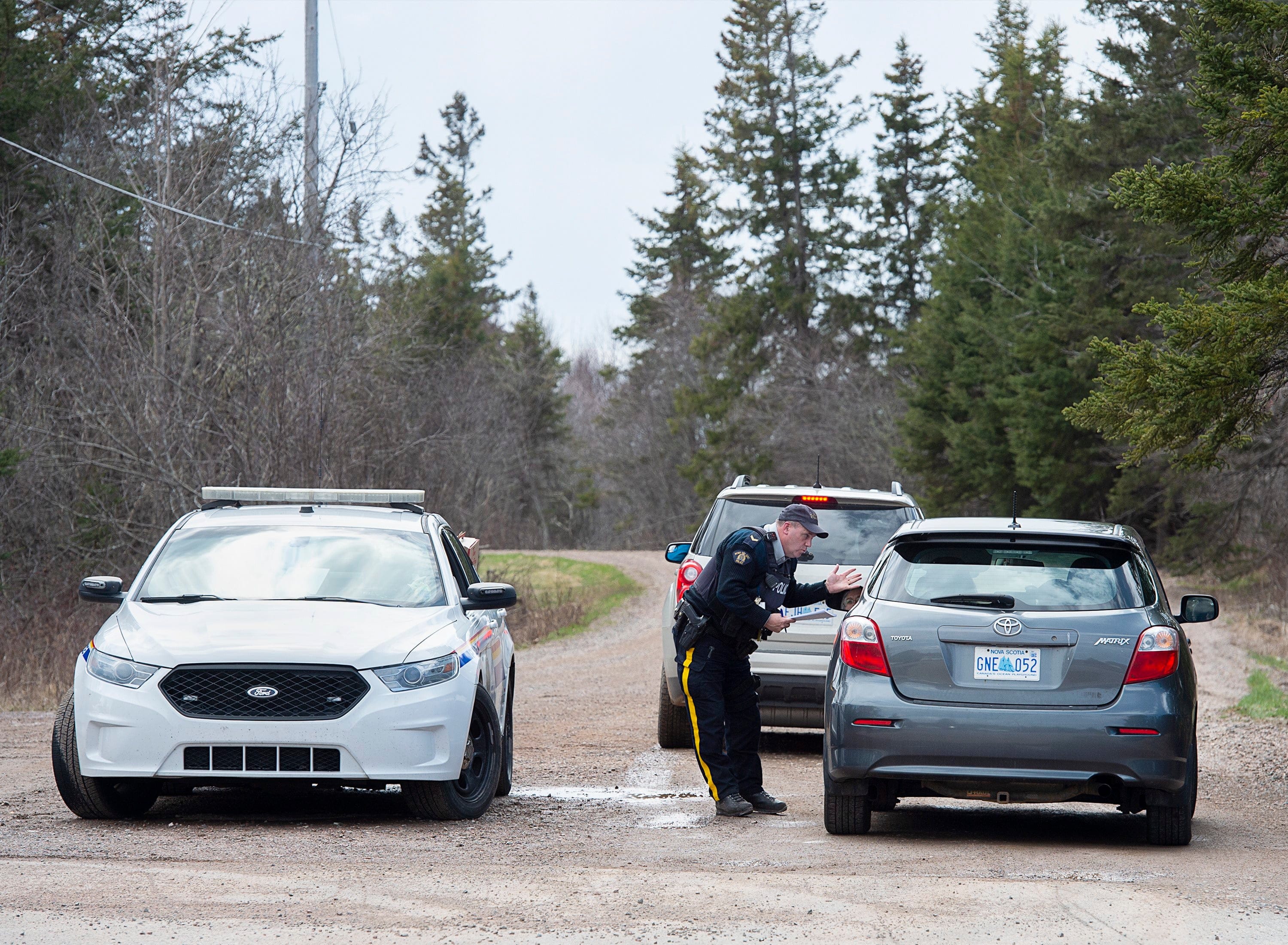 An RCMP officer talks with a local resident before escorting them home at a roadblock in Portapique, N.S. on April 22, 2020 (CP/Andrew Vaughan)