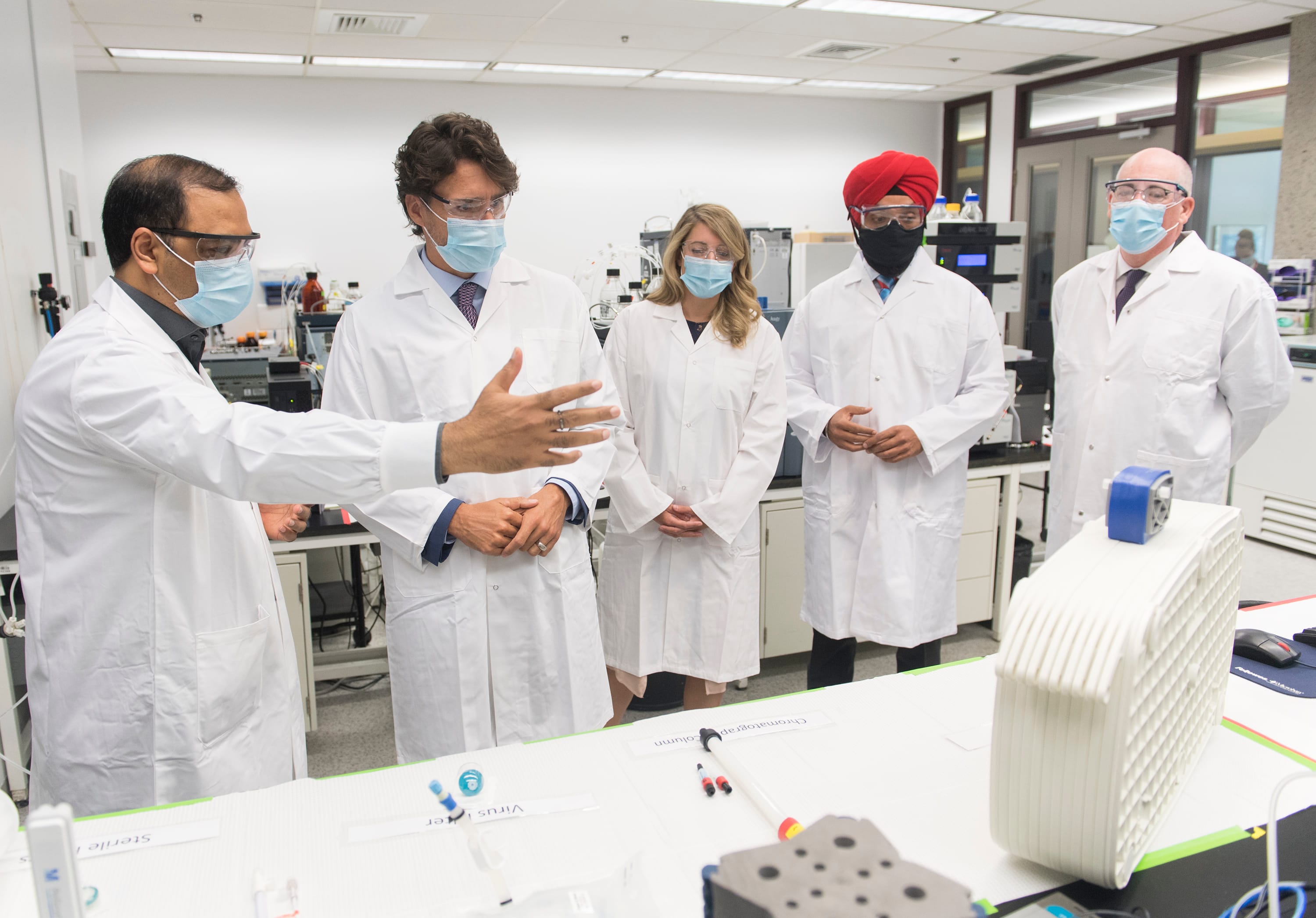 Prime Minister Justin Trudeau, second left, speaks with scientist Krishnaraj Tiwari, left, as Minister of Economic Development Melanie Joly, centre, Minister of Science and Industry Navdeep Bains and NRC President Iain Stewart, right, look on during a visit to the National Research Council of Canada (NRC) Royalmount Human Health Therapeutics Research Centre facility in Montreal, Monday, Aug 31, 2020. (Graham Hughes/CP)
