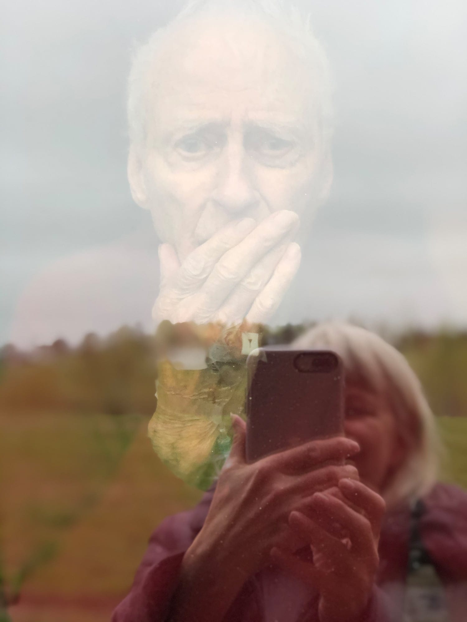 Spalding in the hospital in June, his daughter’s reflection in the window as she takes a photo (Courtesy of Frances Spalding)