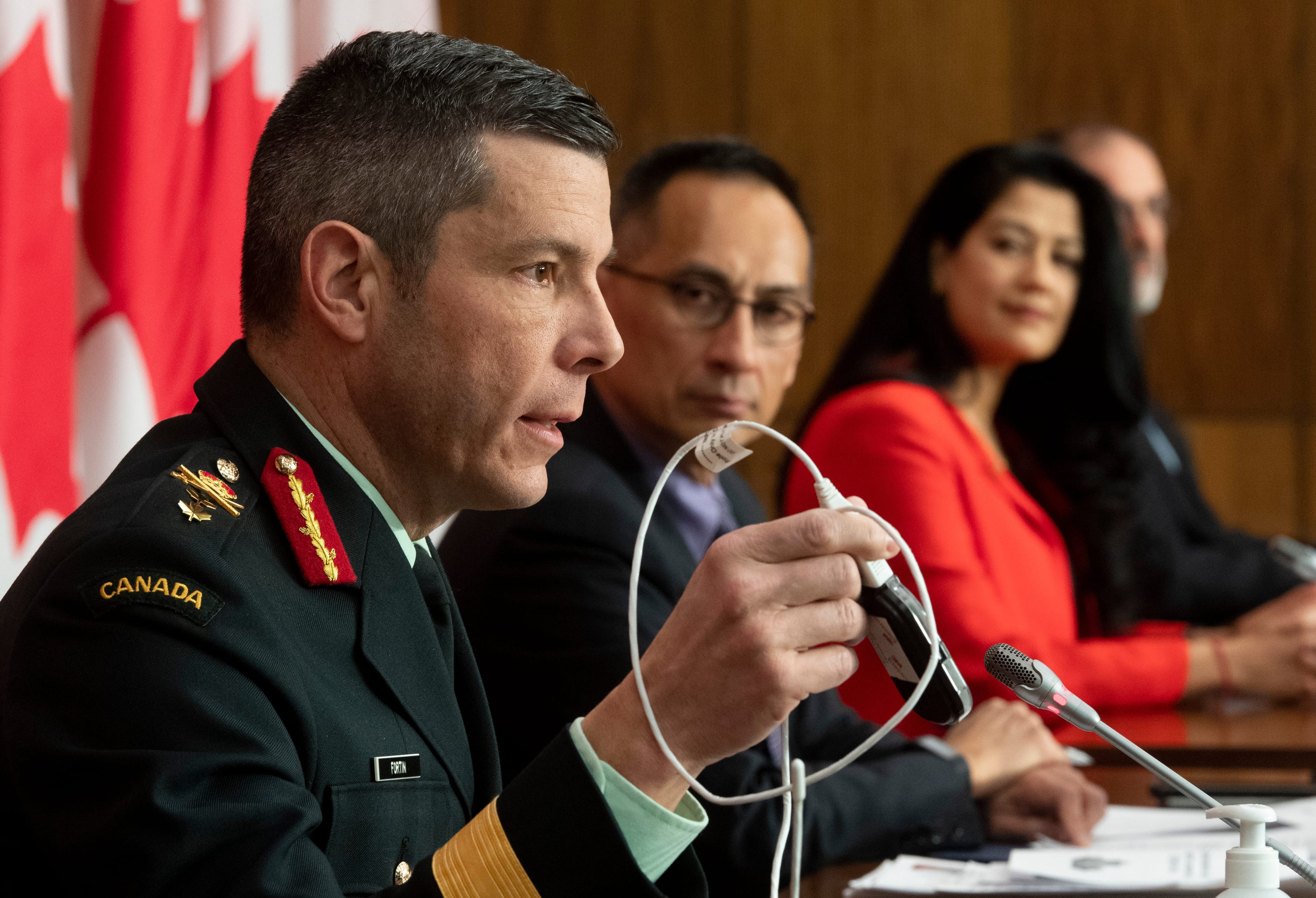 Health Canada's Chief Medical advisor Supriya Sharma and Deputy Chief Public Health Officer Howard Njoo look on as Major General Dany Fortin holds up a device used in the transportation a vaccine during a COVID-19 vaccine-related news conference in Ottawa, Wednesday, Dec. 9, 2020. (Adrian Wyld/CP)