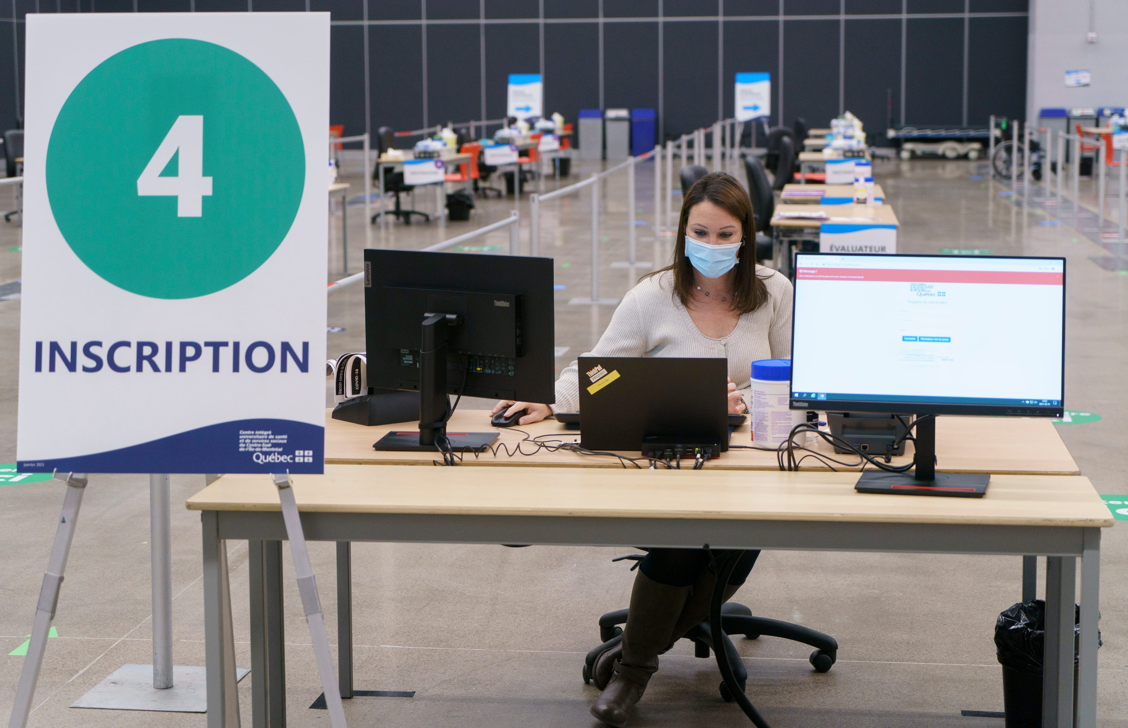 A health care worker works at setting up a registration booth at a vaccination clinic in Montreal, on Monday, February 1, 2021. THE CANADIAN PRESS/Paul Chiasson