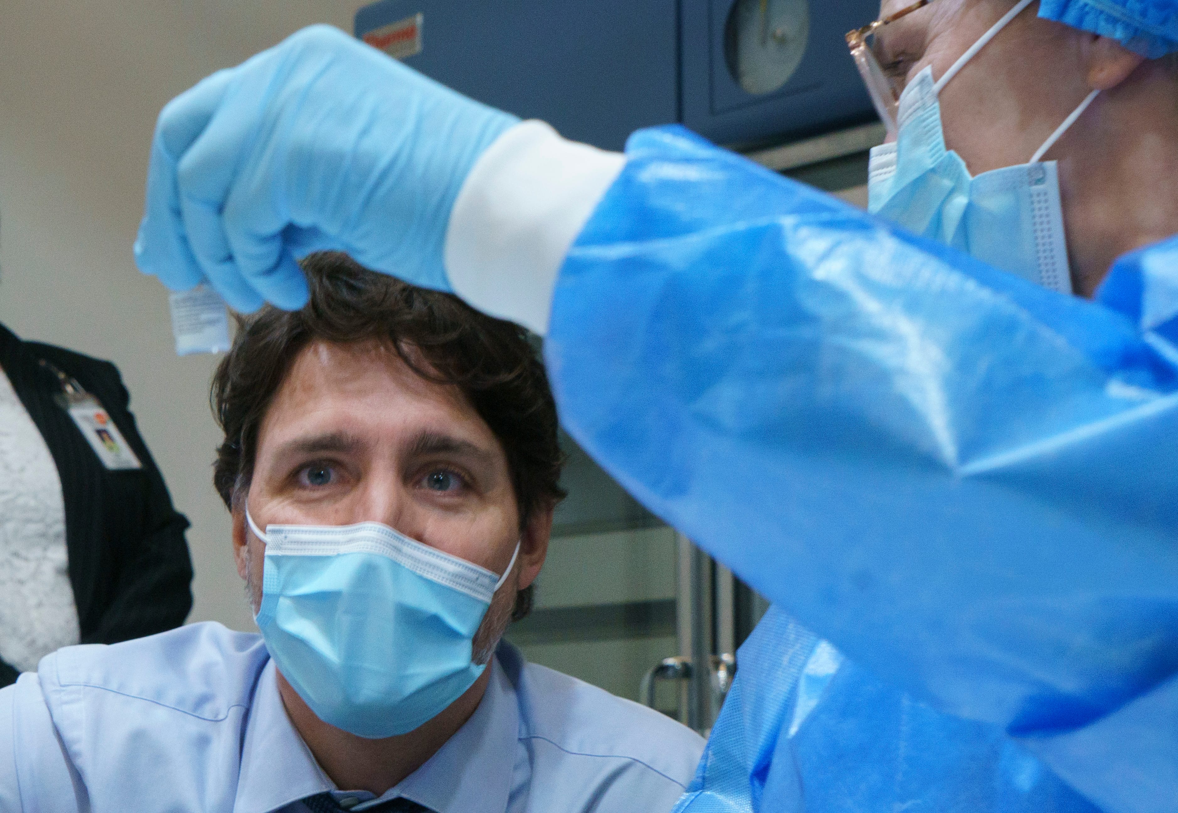 Trudeau looks at a COVID-19 vaccine vial as he tours a  vaccination clinic in Montreal on March 15, 2021 (CP/Paul Chiasson)